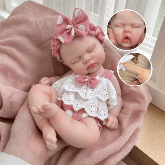 Poupée reborn réaliste de 30cm en silicone souple représentant une petite fille endormie vêtue de vêtements roses à pois