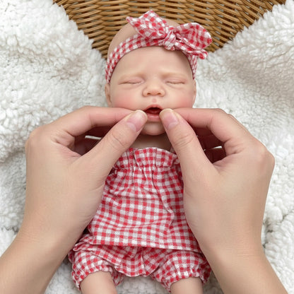 Poupée reborn Pascale en silicone de 30cm avec bouche ouvrante vêtue d'une robe à carreaux rouges