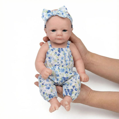 Bébé reborn Felicia de 30cm entièrement en silicone vêtue d'une combinaison bleue à fleurs