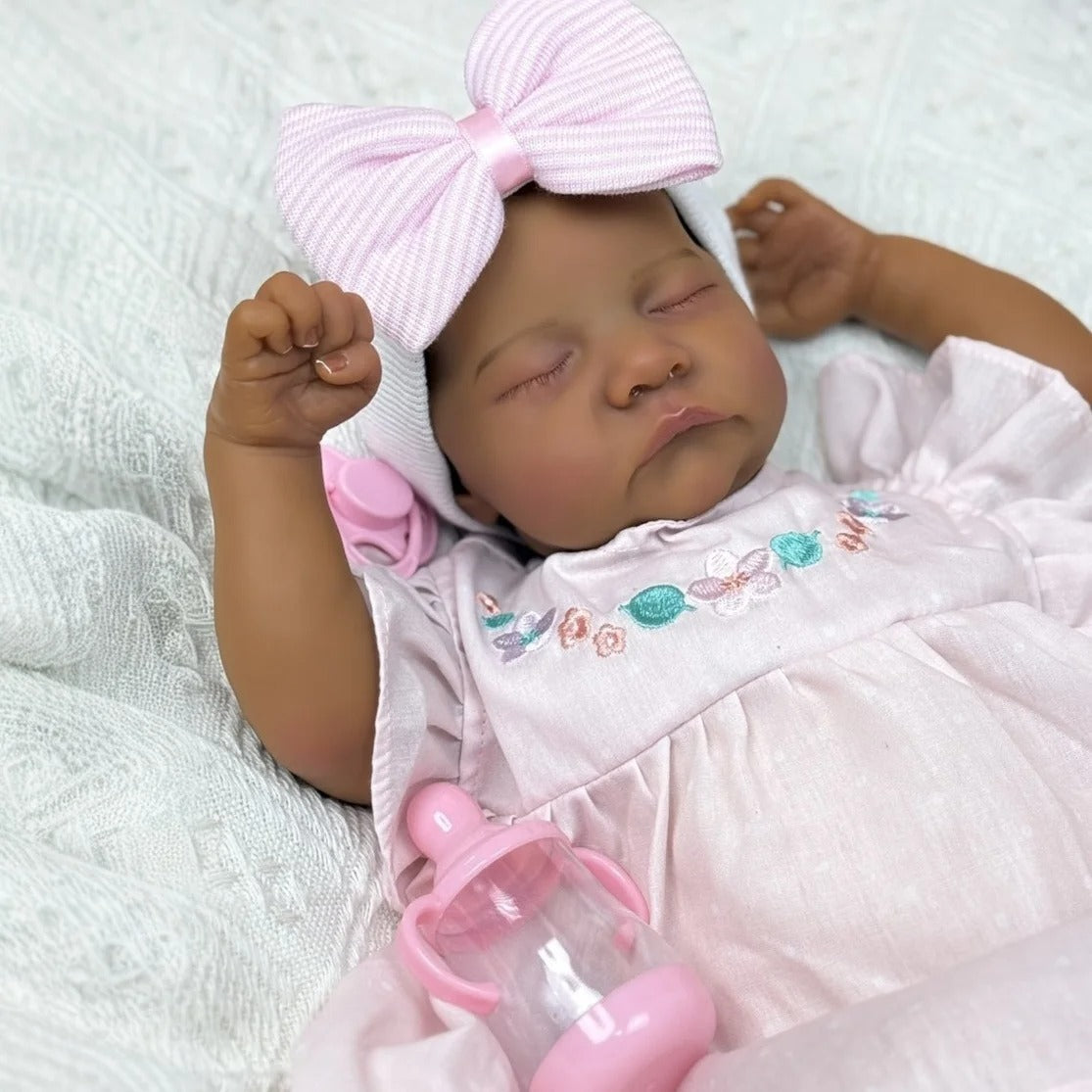 Bébé Reborn Levi de 48cm yeux fermés peau foncée corps doux en robe rose