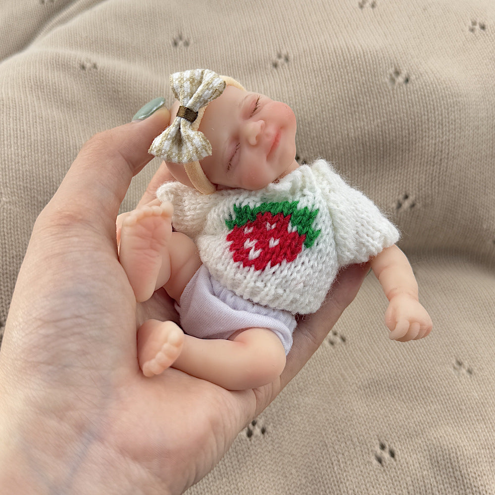 Poupée reborn miniature Pascale de 15 cm yeux fermés en silicone vêtue d'un pull blanc à fraises