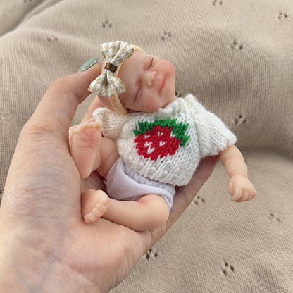 Poupée reborn miniature Pascale de 15 cm yeux fermés en silicone vêtue d'un pull blanc à fraises