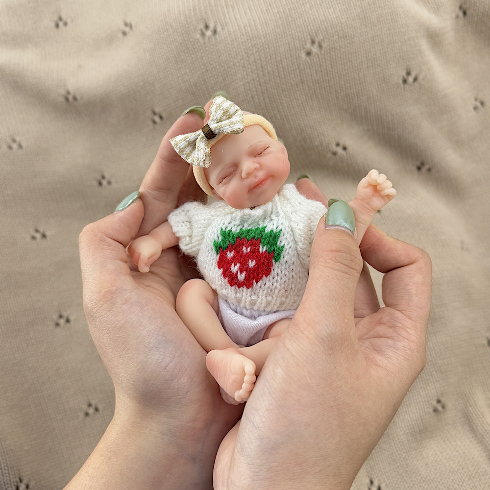 Poupée reborn miniature Pascale de 15 cm yeux fermés en silicone vêtue d'un pull blanc à fraises