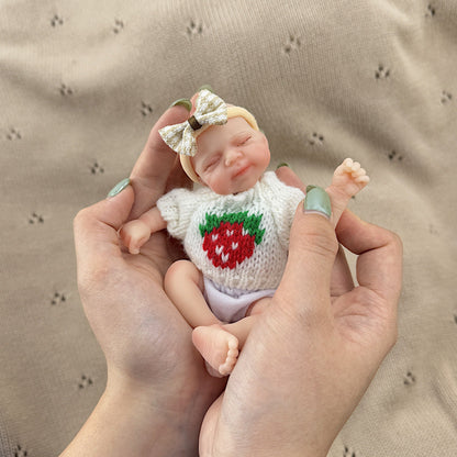 Poupée reborn miniature Pascale de 15 cm yeux fermés en silicone vêtue d'un pull blanc à fraises
