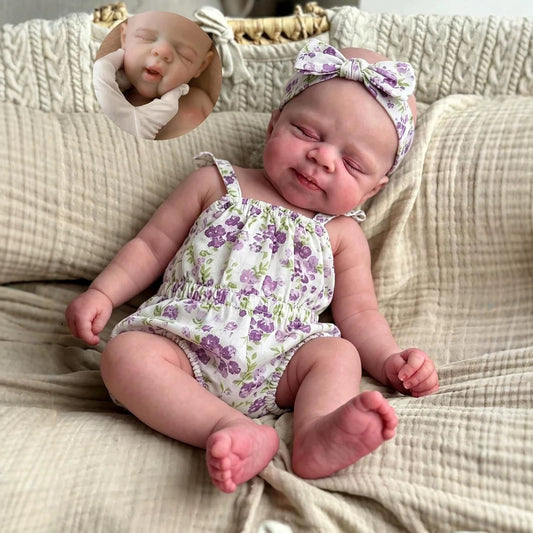 Poupée reborn Pascale de 30 cm entièrement en silicone yeux fermés vêtue d'une barboteuse à fleurs violettes