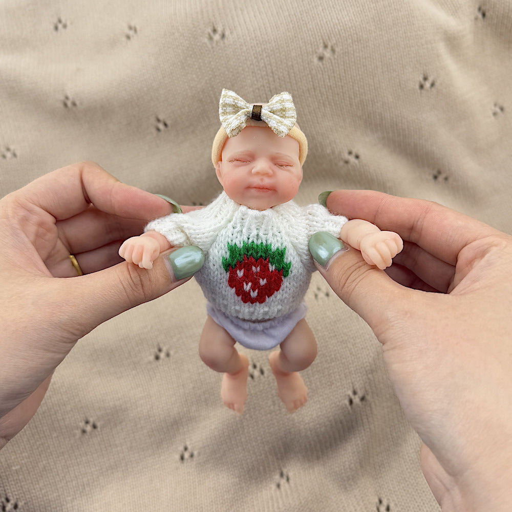 Poupée reborn miniature Pascale de 15 cm yeux fermés en silicone vêtue d'un pull blanc à fraises
