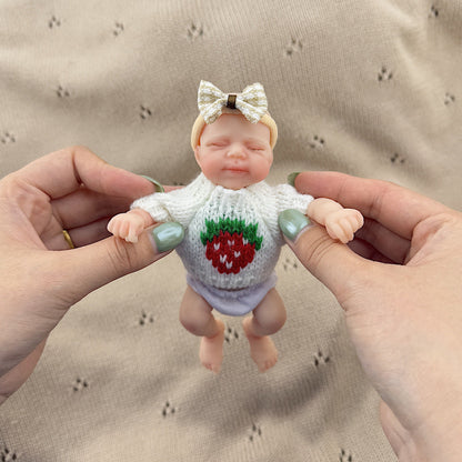 Poupée reborn miniature Pascale de 15 cm yeux fermés en silicone vêtue d'un pull blanc à fraises